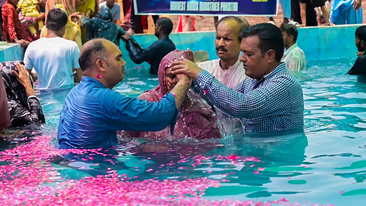 A baptism in water strewn with rose petals
