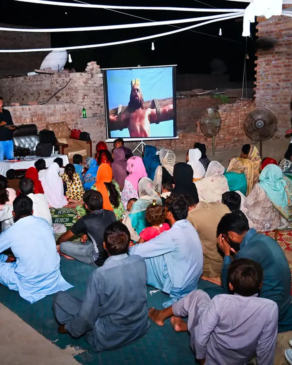 A village watching the crucifixion scene of the Jesus Film, projected in a courtyard after dark
