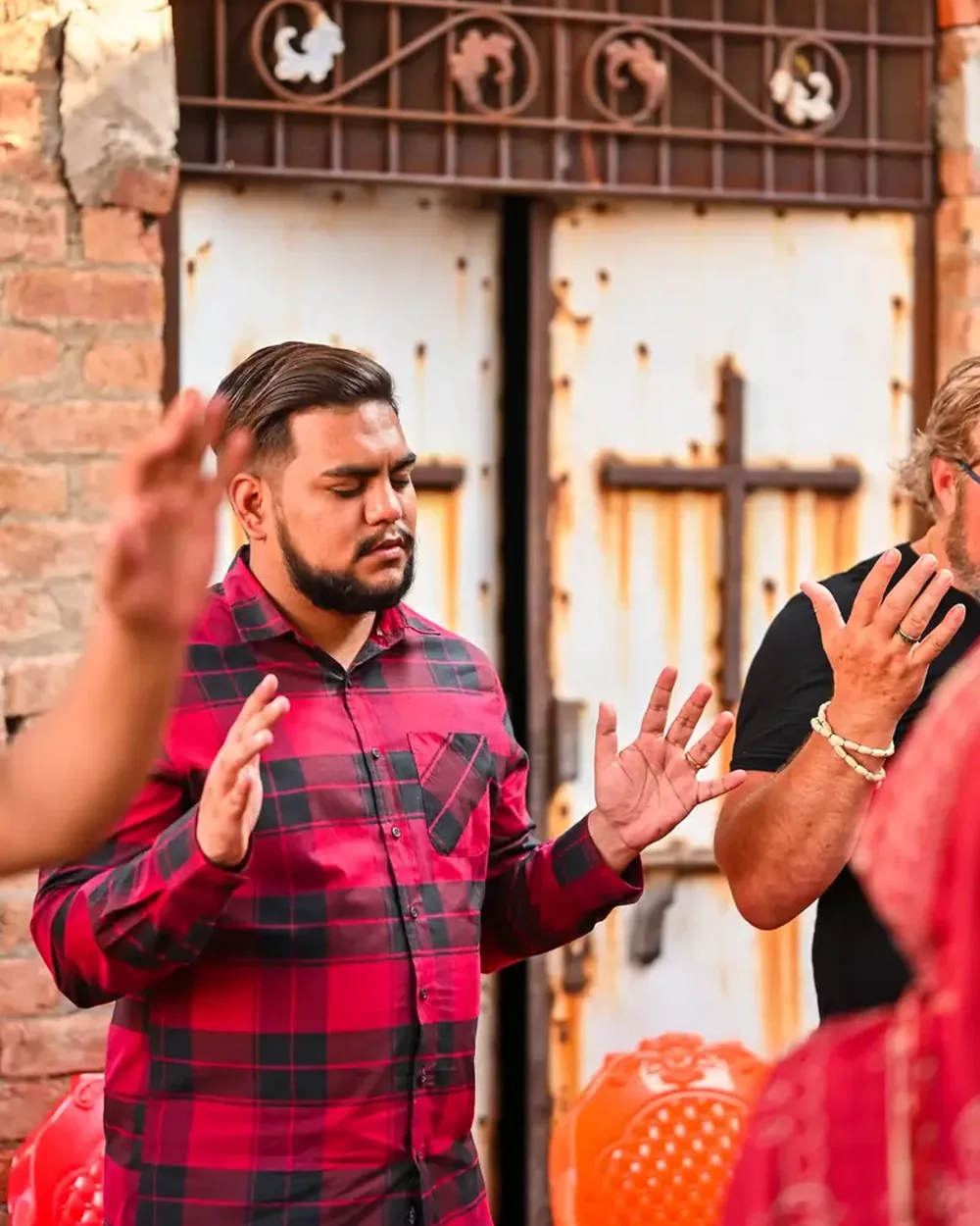 Prayer at an open-air meeting, hands raised beneath the cross