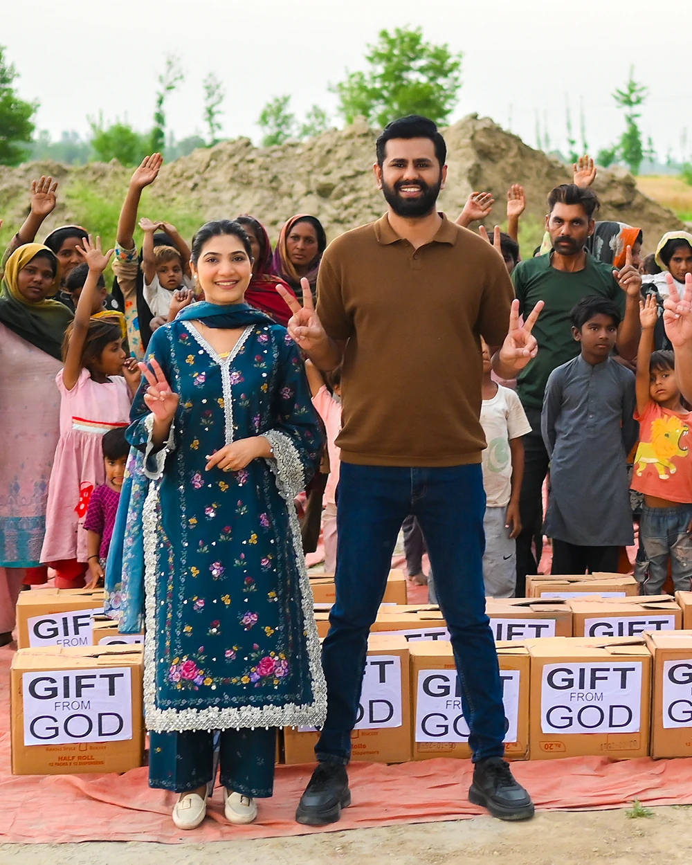 Families raising their hands beside stacked ration boxes marked Gift From God