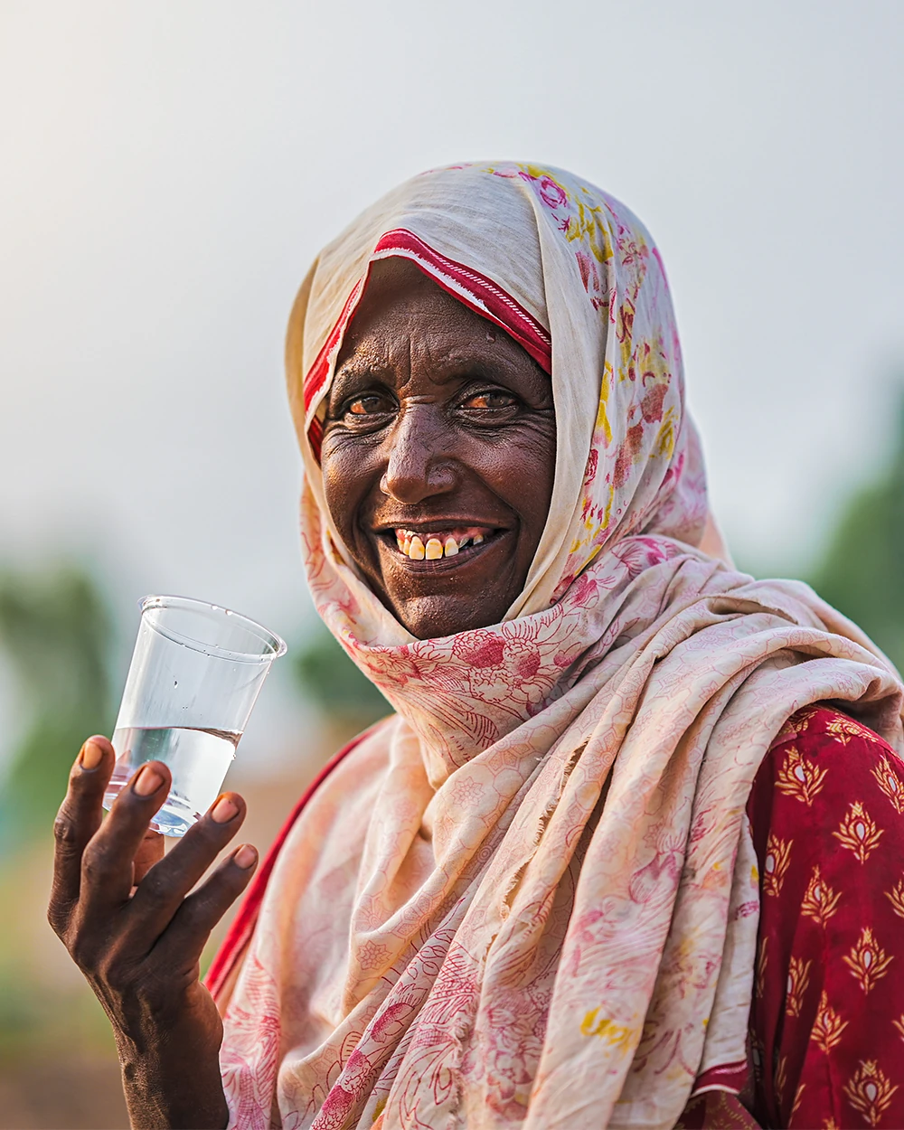 A woman smiling as she holds the first glass of clean water her family has had