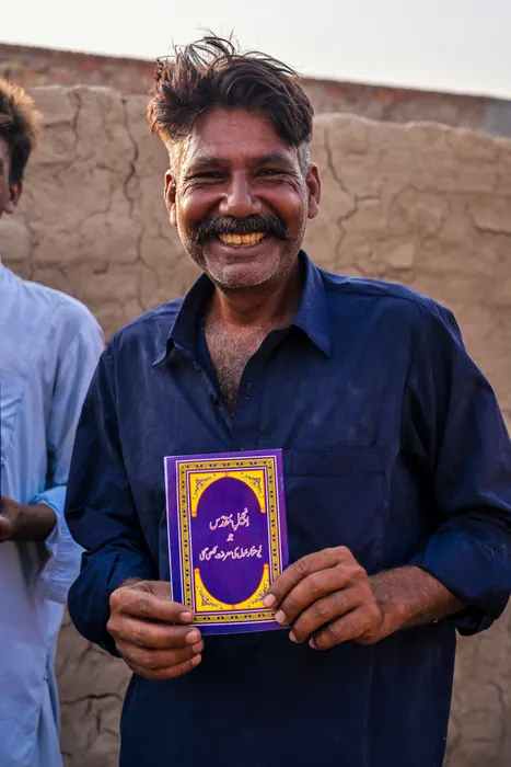 A man holding the Urdu Bible he has just been given