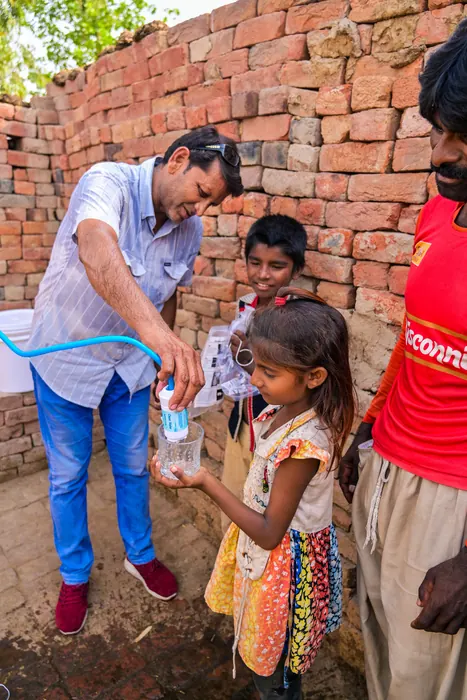 Pouring the first filtered glass for a child at the brick kilns