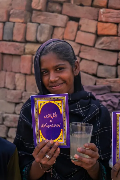 A young woman with her new Bible and the first clean glass of water her family has had