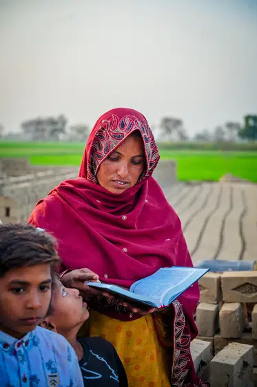 A mother holds her Bible open beside the brick stacks