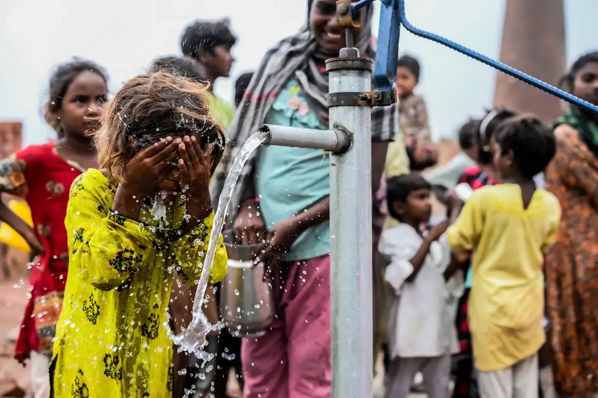 Children crowding a newly installed hand pump